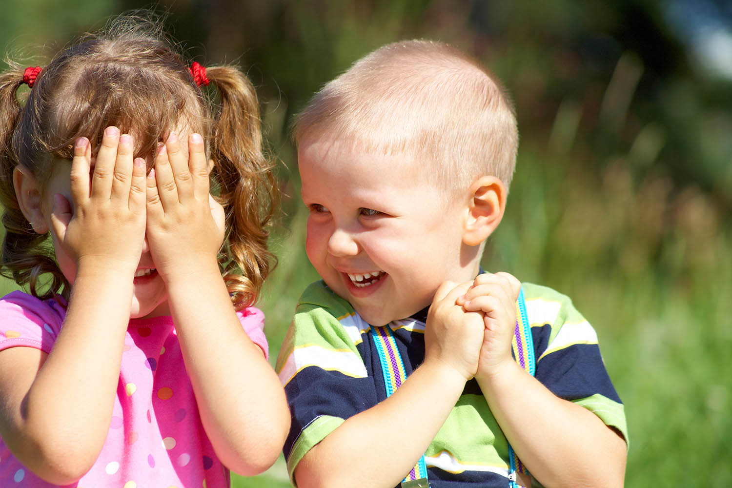 Two funny kids are playing, covering his face with his hands